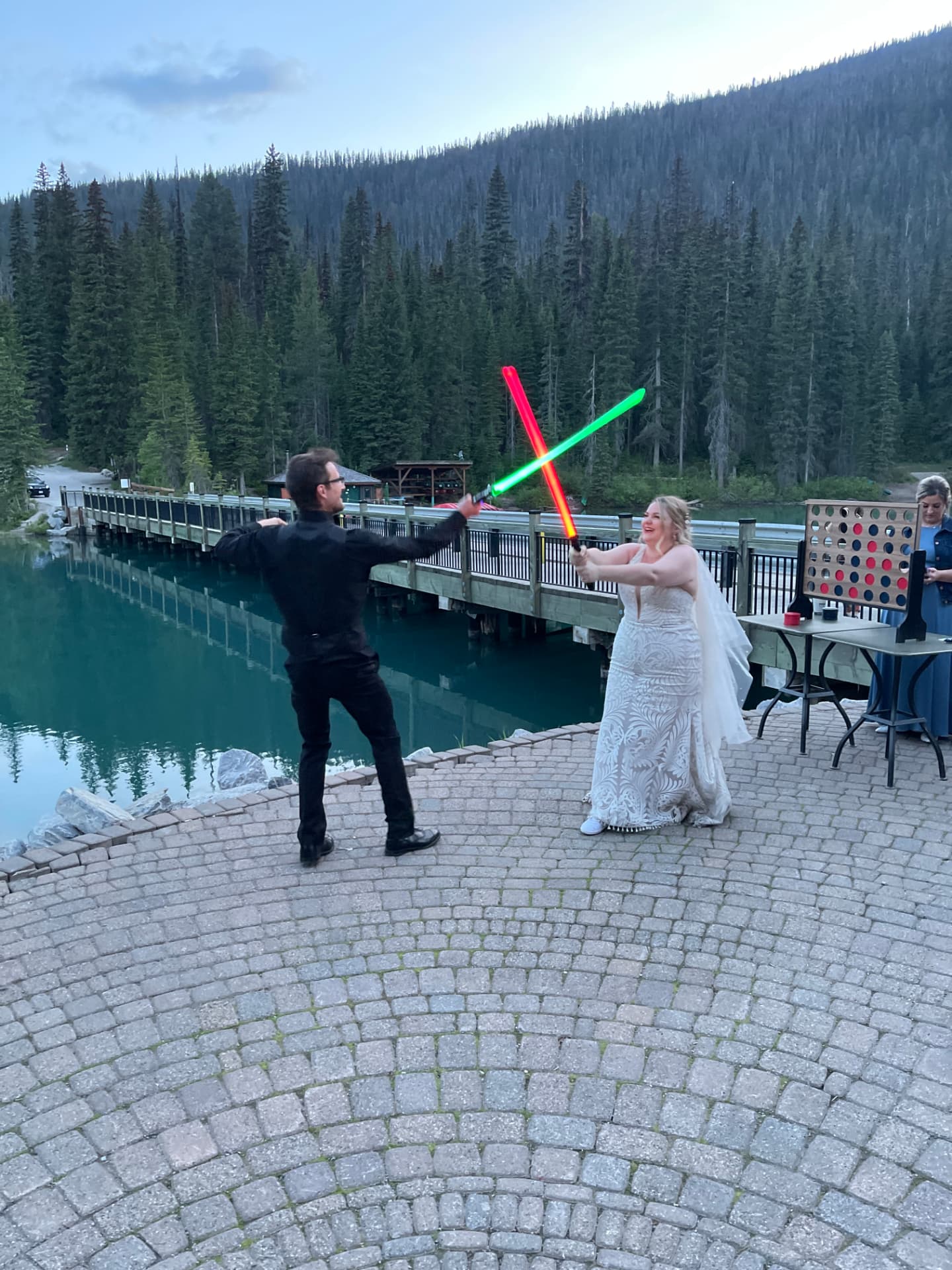 Couple duelling with lightsabers at a mountain lake reception