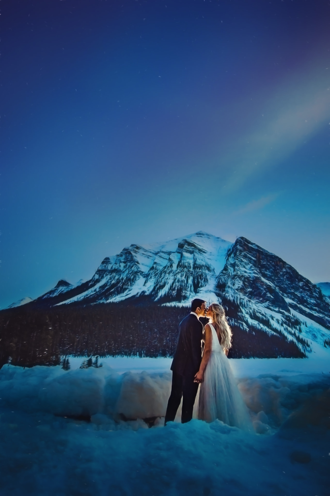 Bride and groom under a starlit winter sky at Lake Louise